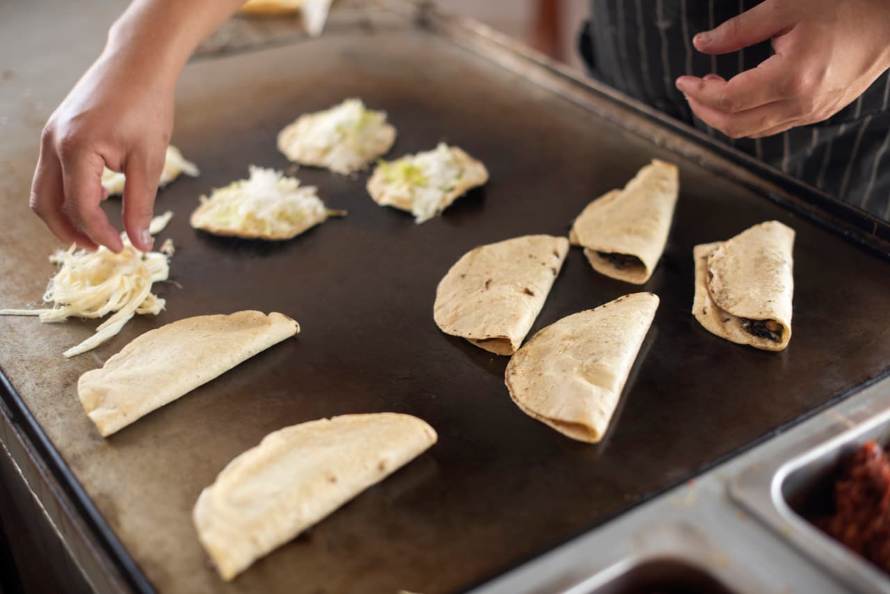 Quesadillas y sopes preparándose a mano sobre el comal