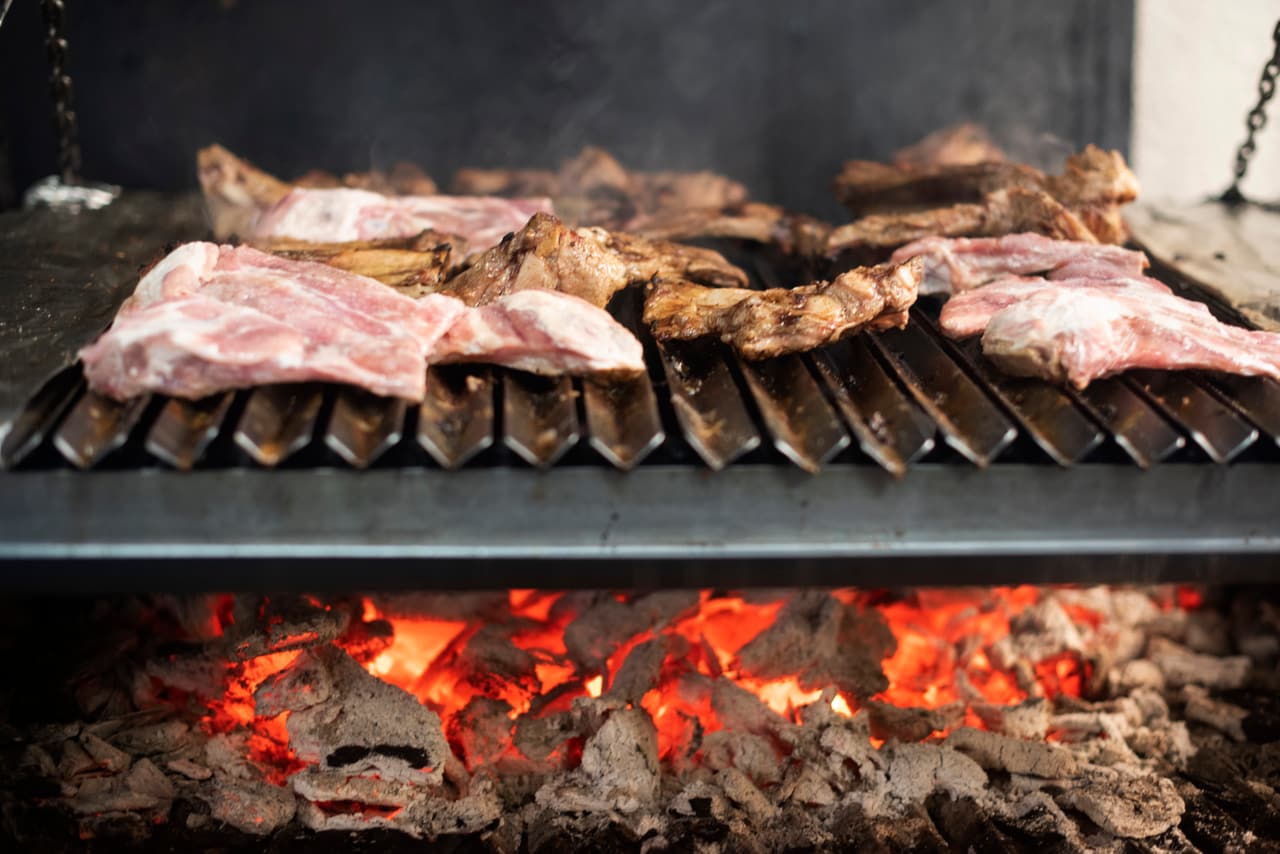 Cortes de carne sobre la parrilla de leña, con brasas encendidas, en Parador del Valle
