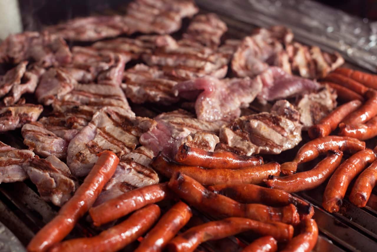 Carnes y chorizo asándose en la parrilla de Parador del Valle