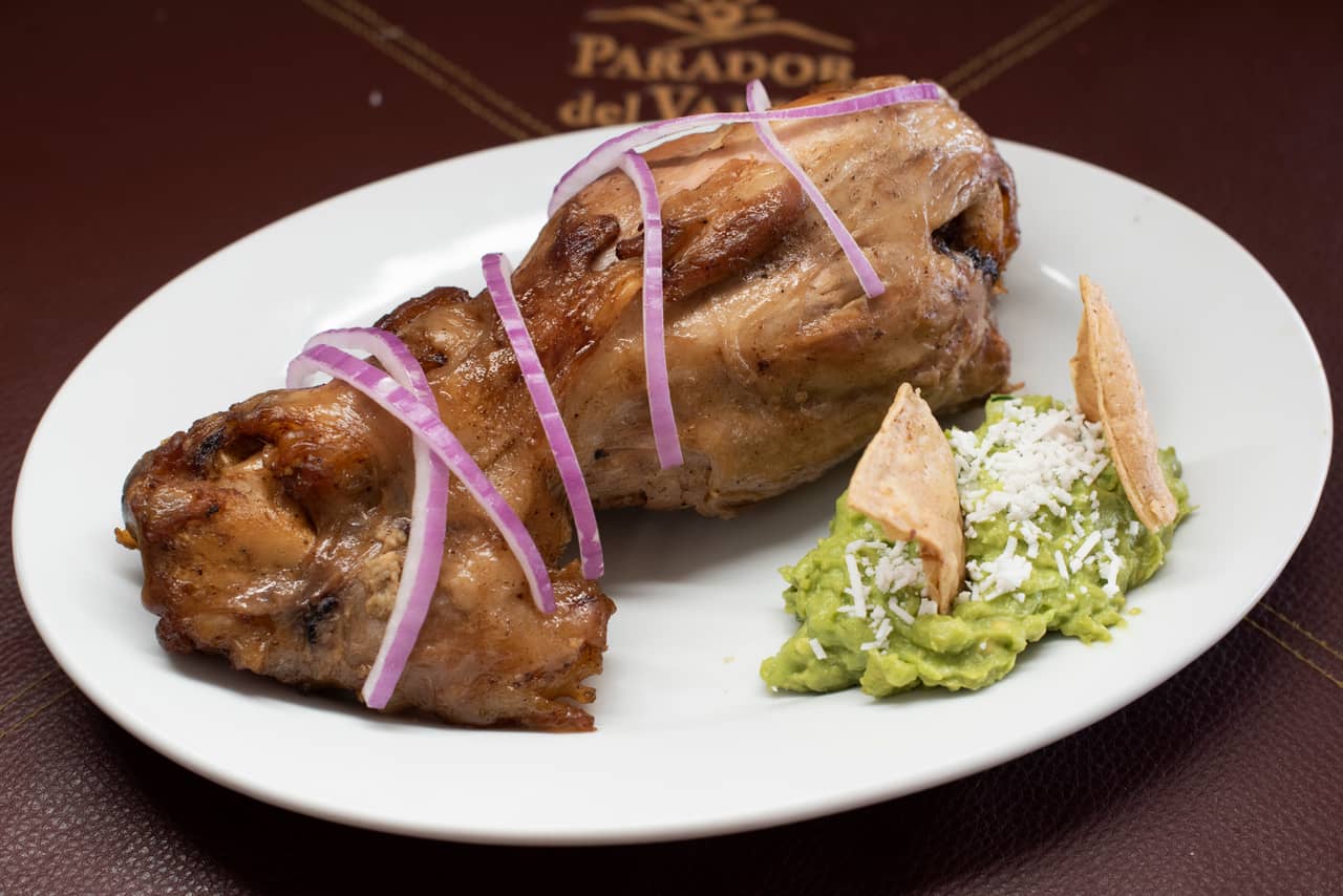 Chamorro dorado con cebolla morada y guacamole servido en Parador del Valle