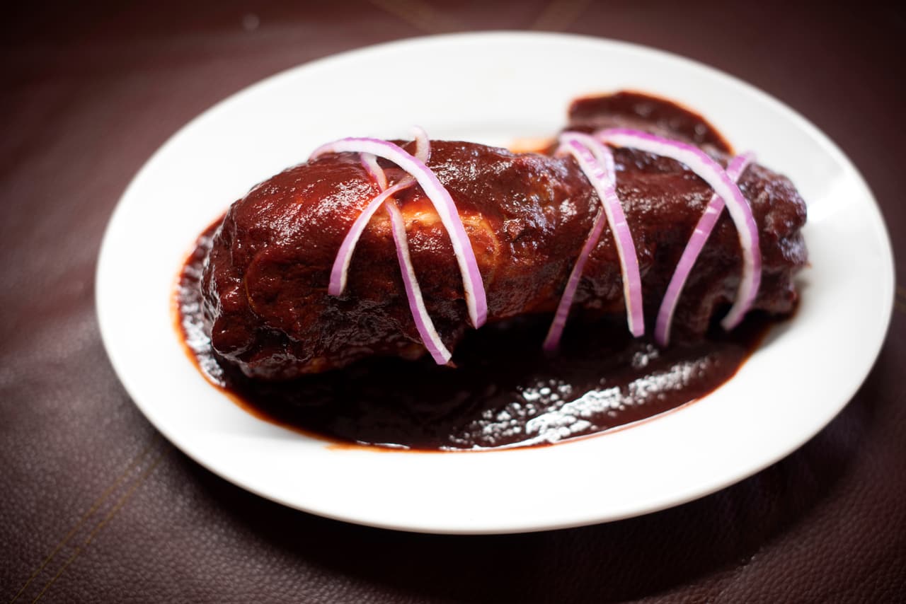 Pollo con mole rojo servido con cebolla morada en Parador del Valle