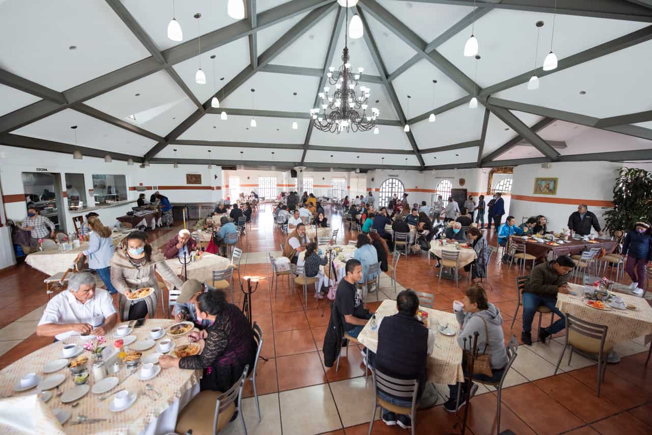 Salón principal de Parador del Valle con techo alto, candil y mesas con comensales